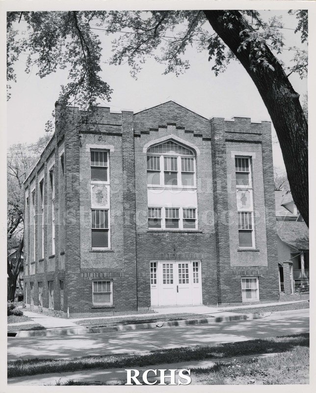 Black and white photograph of First Christian Church, Janesville, WI. Shows a brick church with double wooden doors and a cross on each side of the second floor.