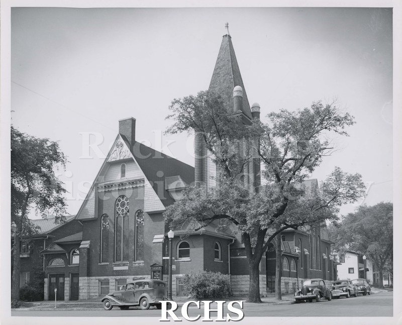 Black and white photograph of First Presbyterian Church, Janesville, WI, with several cars parked in front of it.