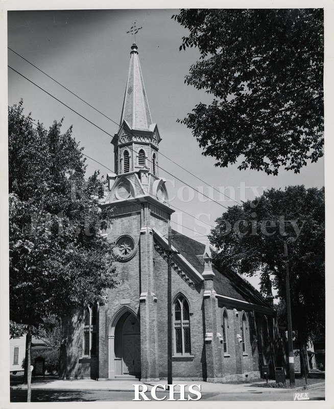 Black and white photograph of St. Paul's Lutheran Church, Janesville, WI. Shows a brick church with a bell tower on top of which is a cross.