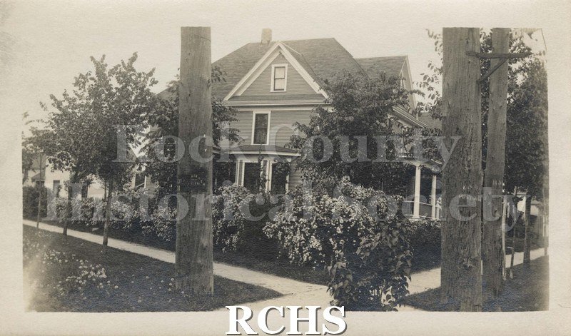 Black and white photograph of Henry Bull home corner/So. Jackson St/ Rockport Road, Janesville, Wis. Shows side view house with medium dark siding and with trim.