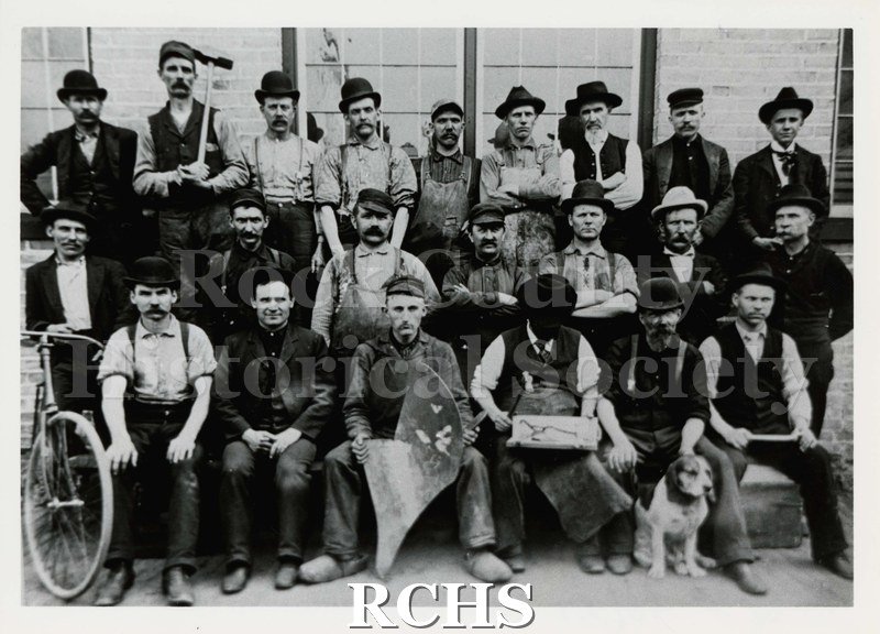 Black and white photograph of Janesville Machine Company. Shows a group of men, seated & standing.