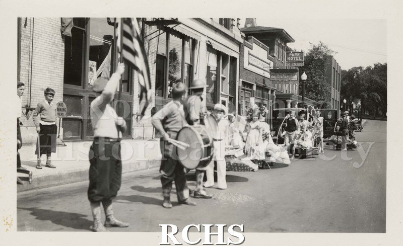 Black and white photograph of Children's Parade, Memorial Day 1933. Shows children in a line in front of stores on street.