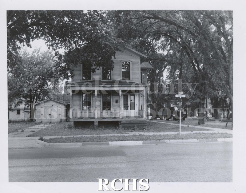 Black and white photograph of house square to front. Two story with front door on right, two windows on left. Three windows across front of house.