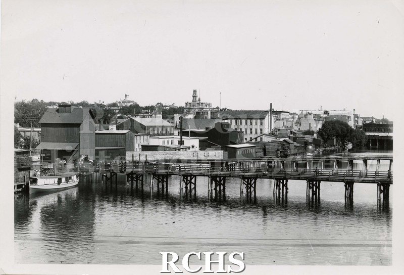 Black and white photograph of the East bank of the Rock River, Janesville, WI., looking south of Rock River in Janesville circa 1900.