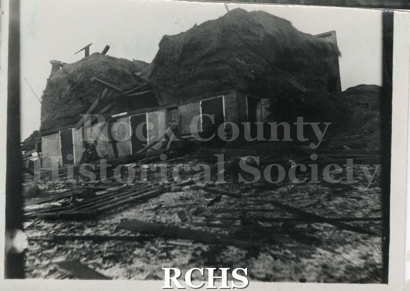 Black and white photograph of tornado damage 1911. Shows a building demolished in the tornado. Debris is visible in front of the building.