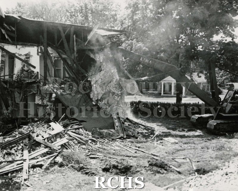 Black and white photograph of the demolition of Wright-Amato House. Crane is on the right with debris in front of the house.