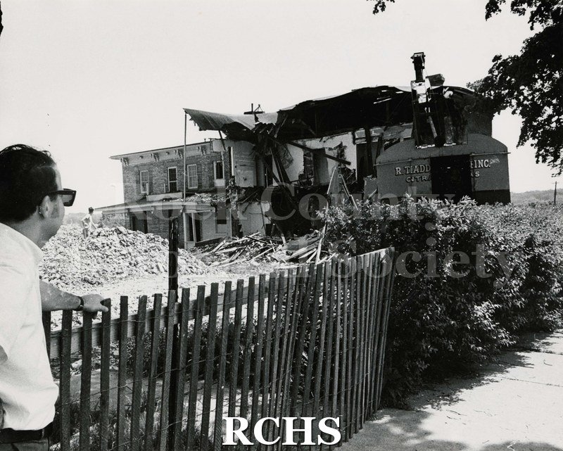 Black and white photograph of the demolition of Wright-Amato House. There is a man observing on the left.