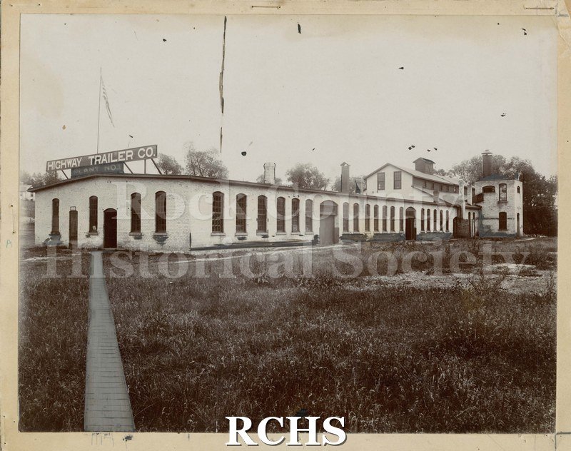 Black and white photograph of Plant No. 3 Highway Trailer Co., Edgerton, WI. Shows a factory building with "Highway Trailer Co. Plant No. 3" sign on top.