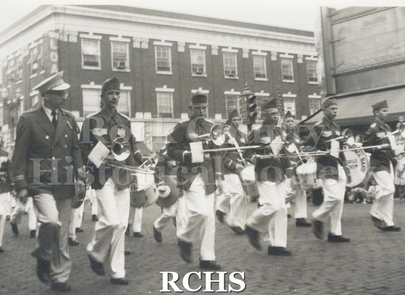 Black and white photograph of Rock County Rural Band marching down a street.