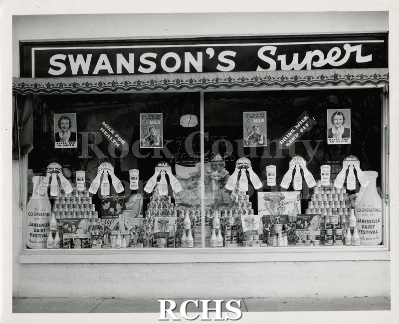 Black and white photograph of Swanson's Super Market. Shows store window. "Swanson's Super" on top over awning with border.