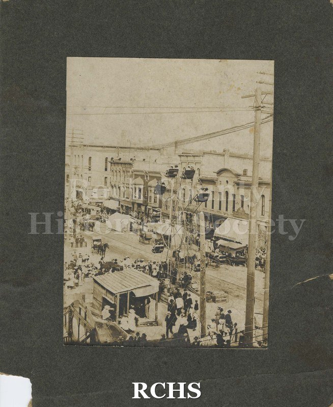 Black and white photograph of Carnival in Janesville, Milwaukee Street, circa. June 1896. Downtown Janesville from upper floors of a building.