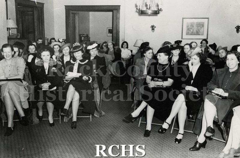 Black and white photograph of several women sitting on chairs facing the camera.