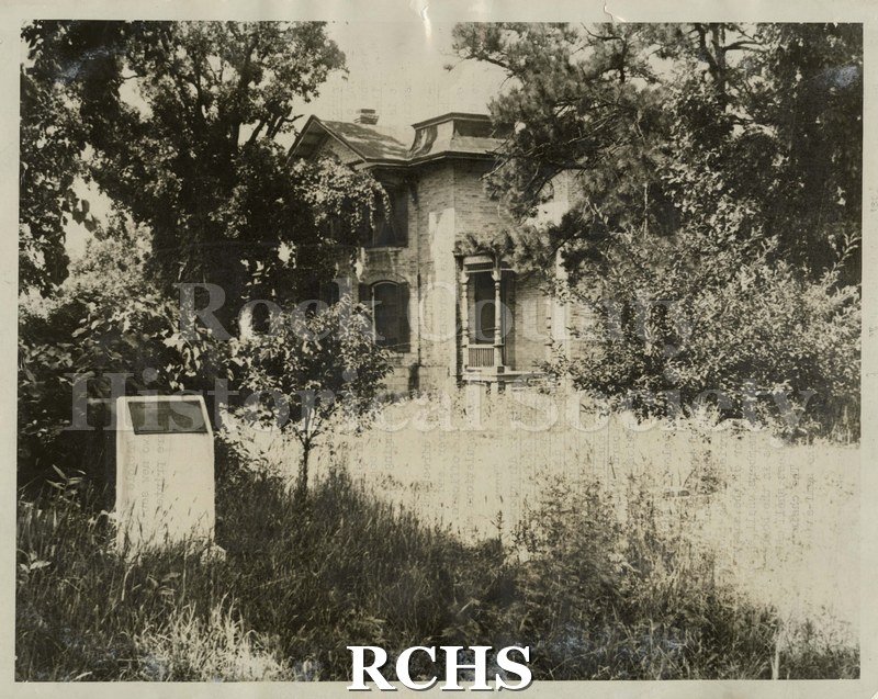 Black and white photograph of_x0002_Baines residence, c. 1870, a two story house surrounded by trees. There is a marker on the left side.