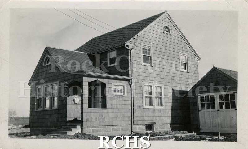 Black and white photograph of Chester Welch Residence. This is a two story house with a garage on the side.