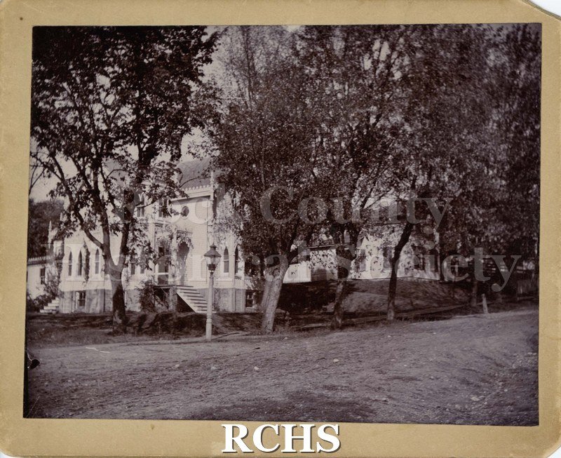 Black and white photograph of Woodruff House 1890. Shows a two story house with trees in front of it.