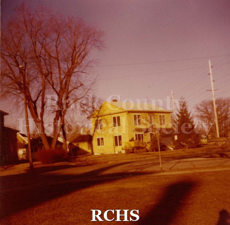 Photograph .color photo of the home at 485 N. Jackson St.., Janesville, WI (Razed March 7, 1977). Shows a two story house which appears yellow in color.