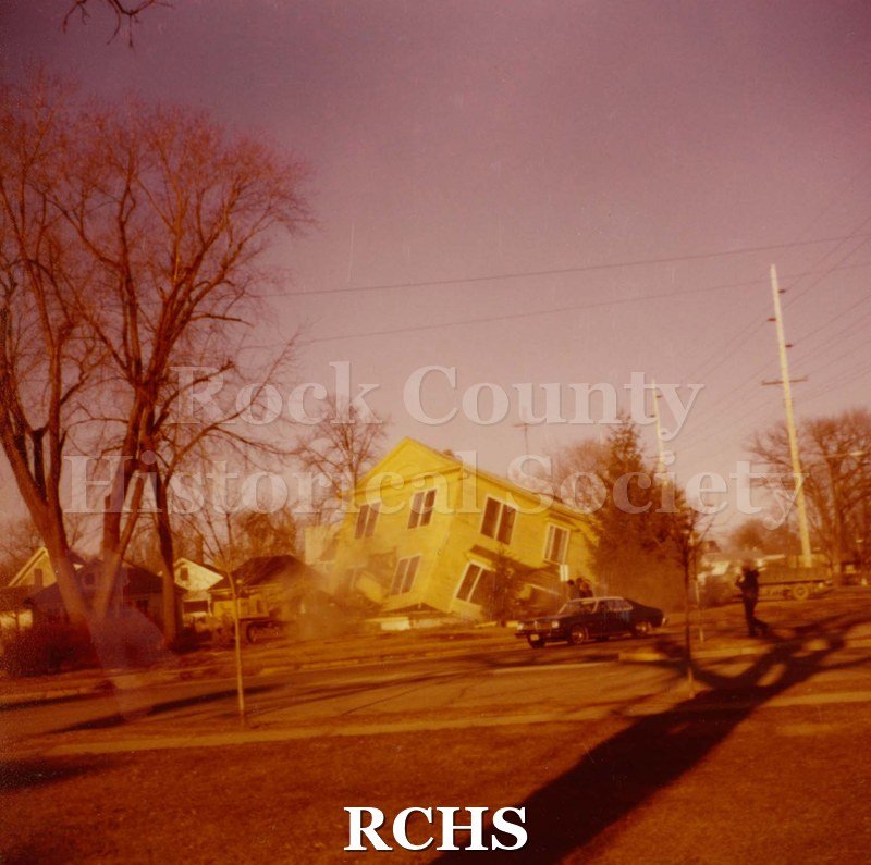 Color photo of the home at 485 N. Jackson St.., Janesville, WI (Razed March 7, 1977). Shows a two story house which appears yellow in color.