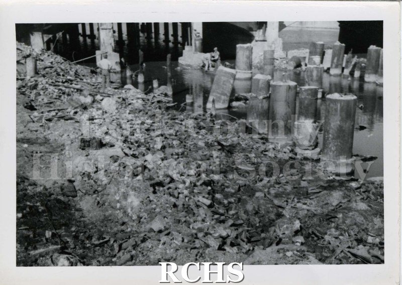 Black and white photograph of pilings left in the river after the fire.