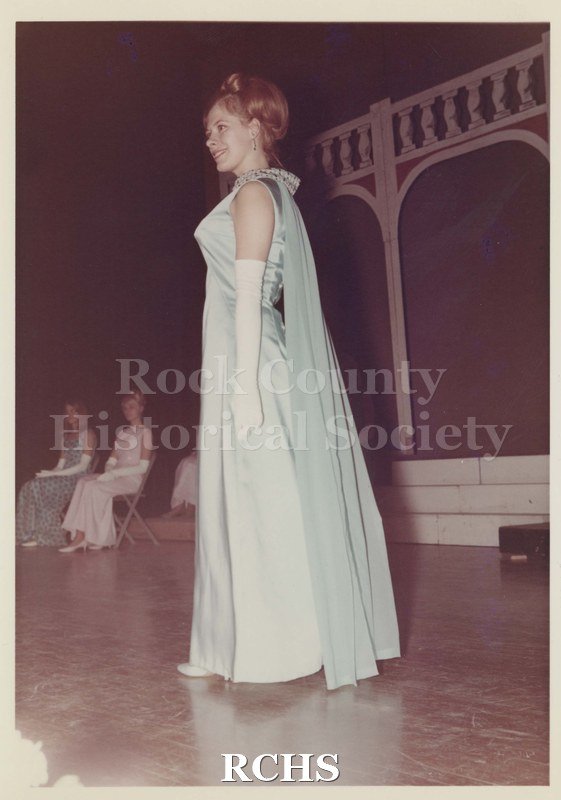 Colored photograph of Jennifer Kreuser, Contestant Miss Janesville Pageant 1968, wearing a blue formal dress with a train.