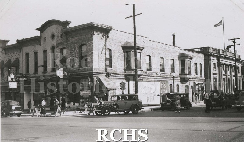 Black and white photograph of Sid Weber Front before 1936. One sign above door reads "Drug"; to the left is a sign for "Central Restaurant".