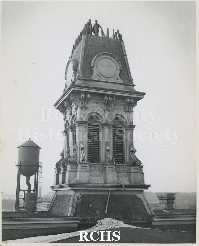 Black and white photograph of Old Court House(?), showing a tower with two workmen on the top.