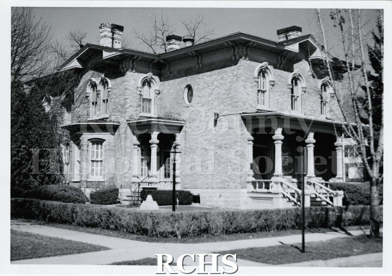 Black and white photograph of side view of Durkee-Tallman-Henning house, a two story brick building with chimneys on the roof.