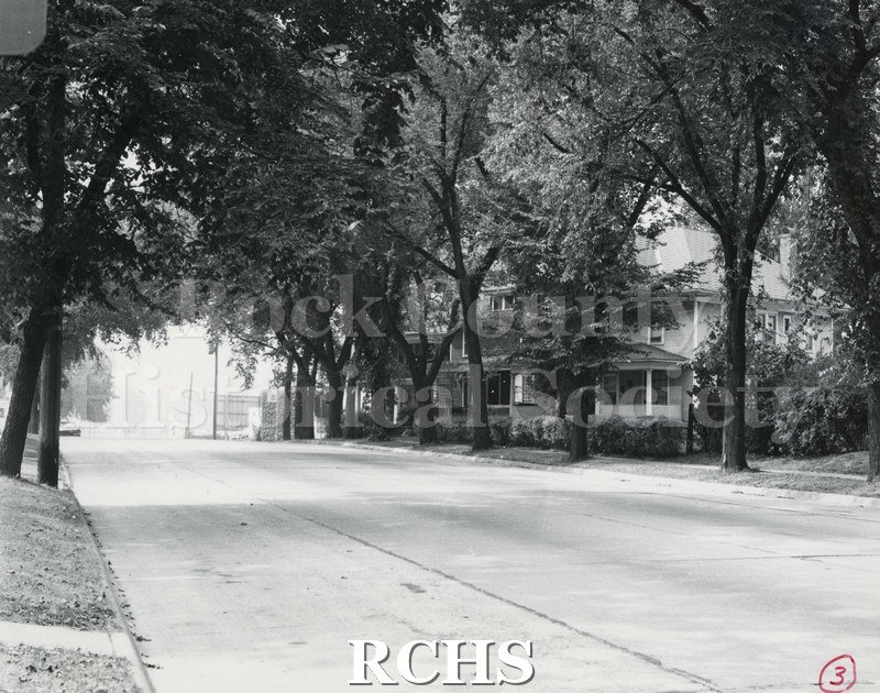 Black and white photograph of Court Street with a three story house visible through the trees.