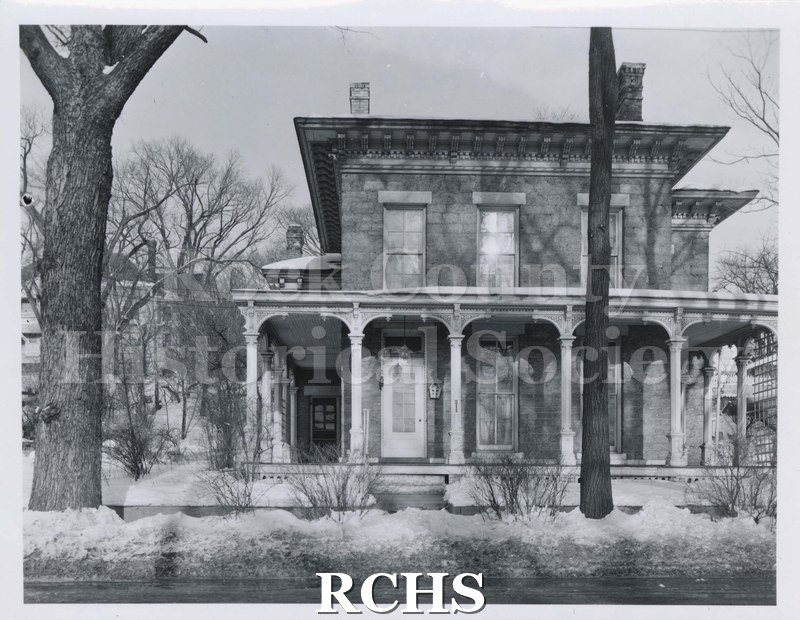 Black and white photograph of the Alden Family home, a two story house with a pillared porch along the front. Residence of Peter J.