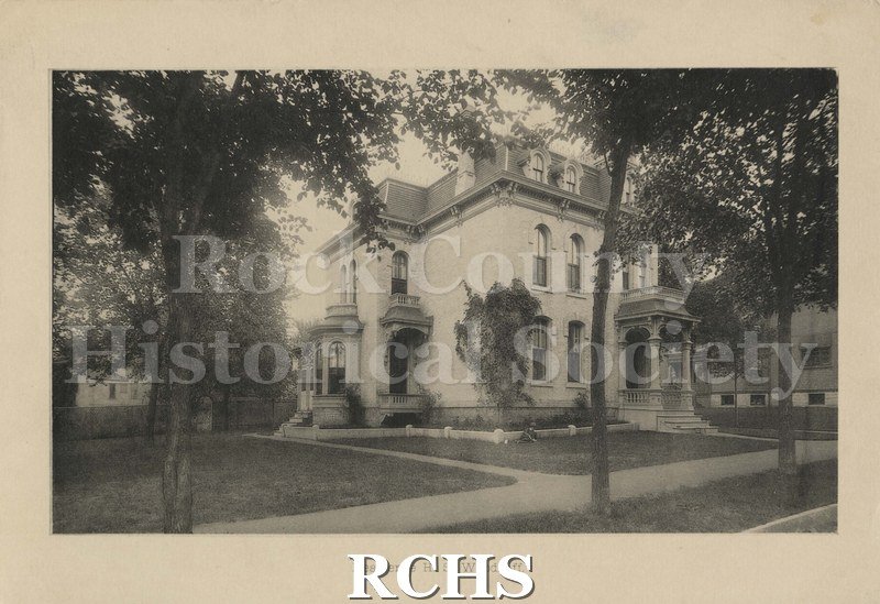 Black and white photograph of H. S. Woodruff's home, a three story brick house with a porch on the front and an enclosed porch on the side. On bottom: "Residence H.