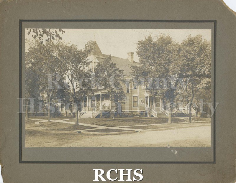 Black and white photograph of 119 S. Wisconsin Street, a three story house with a porch on the front and one on the right side.