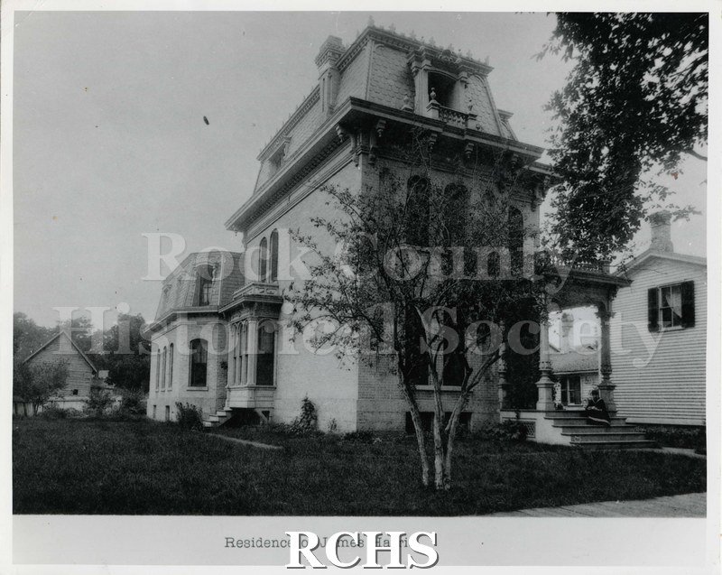 Black and white photograph of 170 South Jackson St., a three story house with a pillared porch on the front. There is a person sitting on the steps.