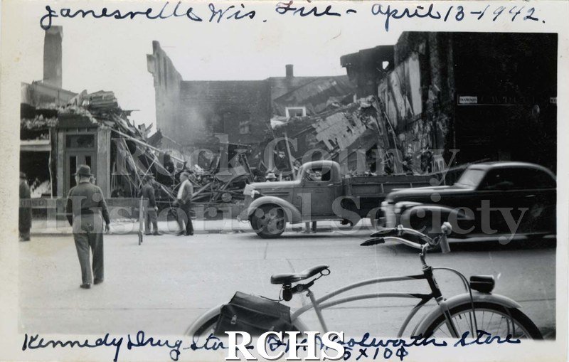 Black and white photograph of Janesville Wis. Fire April 13-1942. Shows buildings that have been demolished and people standing nearby.
