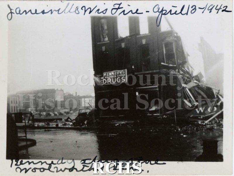 Black and white photograph of Janesville Wis. Fire April 13-1942. Shows a building partially demolished with sign: "Kennedy Walgreen System Drugs" on it.