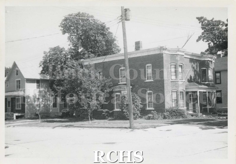 Black and white photograph of 201-203 S. High Street, an apartment building shown from the side. There is a porch on the front.