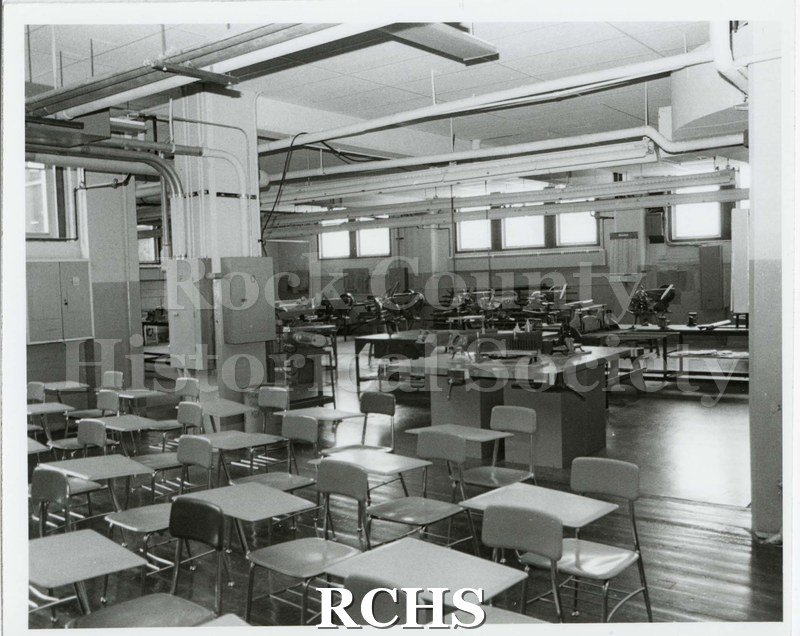 Black and white photograph of the Machinery Shop Marshall Middle School containing desks and machinery.