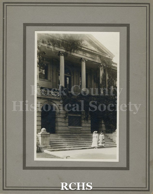 Black and white photograph of Pearl Tramblie and Mrs. J. Warren Hahne standing on the steps of the Janesville Public Library.