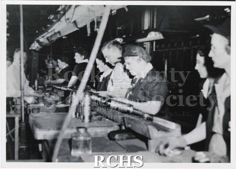 Black and white photograph of men and women working on a line at the Janesville Fisher Body factory, in 1944.