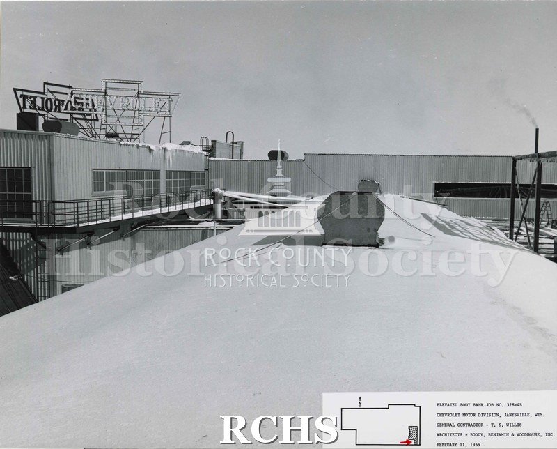 Black and white photograph of the roof of the factory building. There is a vent on top secured with wires. To the left is the Chevrolet sign in reverse.