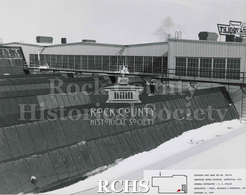 Black and white photograph of the roof of the factory building. There is snow on the right side of the photo. Also the Chevrolet sign is on the right in reverse.