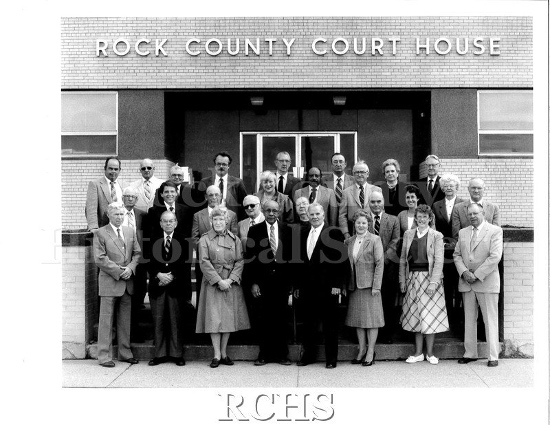 Black and white photograph of Rock County Board of Supervisors, April 1, 1988. Shows several men and women standing in front of the Rock County Court House.