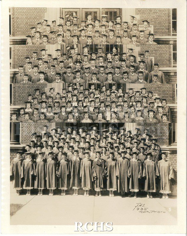 Tinted photo of the 1935 Graduating Class. Shows graduates wearing caps and gowns, tassels hanging to the left.