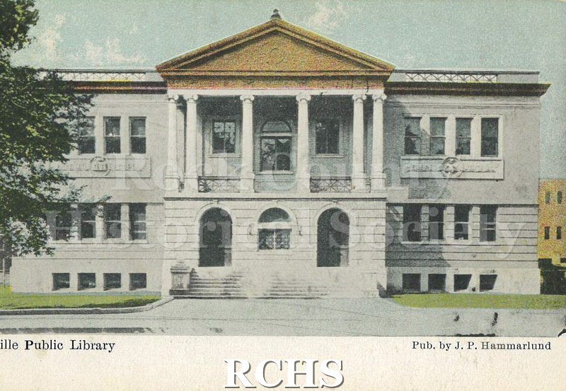 Postcard. Colored image of the Janesville Public Library. Exterior view taken from Main Street in front of the building. Published by J.P. Hammarlund.