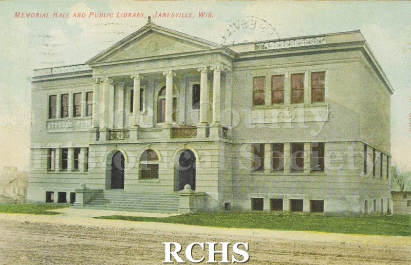 Postcard. Colored image of Memorial Hall and Public Library in Janesville. Image of the exterior is taken from Main Street before the road was paved.