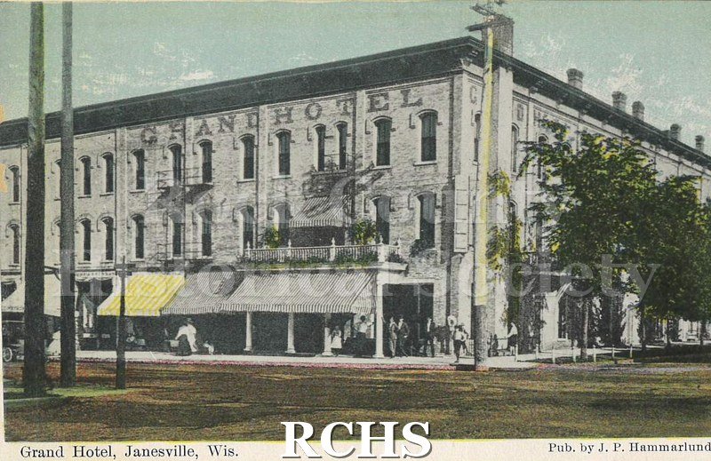 Postcard. Colored postcard of the exterior of the Grand Hotel in Janesville. The hotel name is painted along the top of the third floor.
