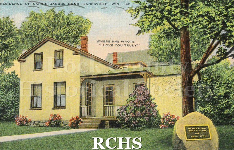 Linen postcard of the residence of Carrie Jacobs Bond in Janesville. The color image shows the exterior of her house in early summer when the lilacs are blooming.