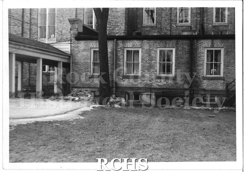 Black and white photograph of the side of the original building for the First Congregational Church. Covered porch area is visible on the left side of the photo.