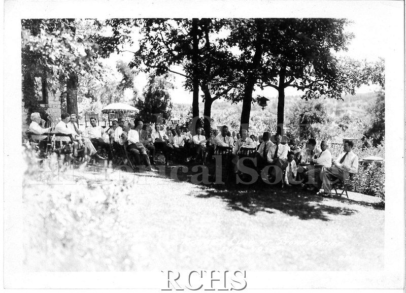 Black and white photograph of several men sitting on chairs on the lawn in front of a house. On bottom, in white: "Rotary Club at Stone Hende July, 1930 Rex".