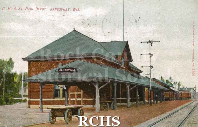 Postcard. Exterior view of the train depot in Janesville. No trains included on the card. Postcard is addressed to Mrs. Charles Benedict in Hebron, Illinois.
