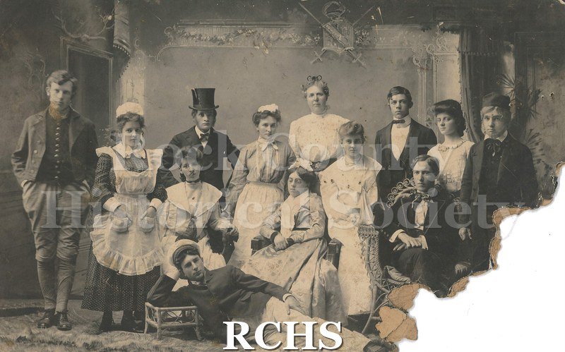 Black and white photograph of the cast of a Janesville High School play in 1904. Cora Soverhill Atwood plays the old lady in the center.