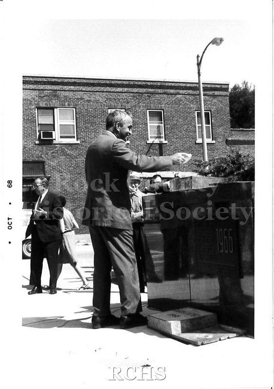 Black and white photograph of man standing near the granite dedication slab.